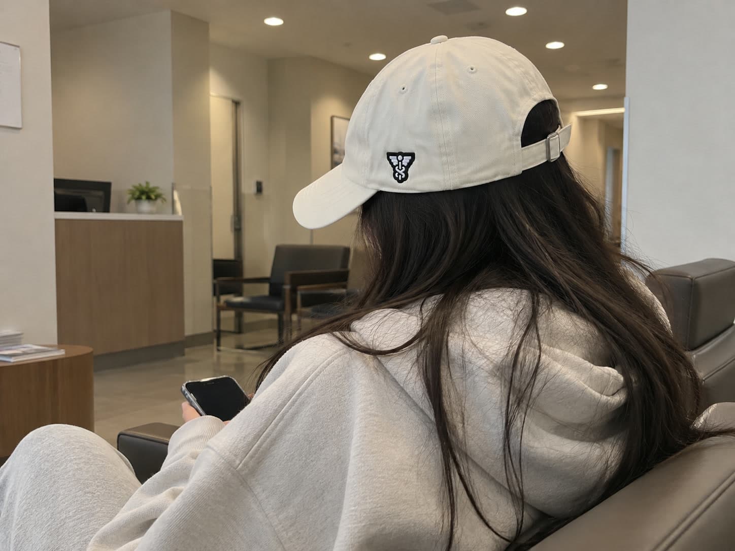 The Sallet worn from behind in a waiting room, the symbol patch on its side.