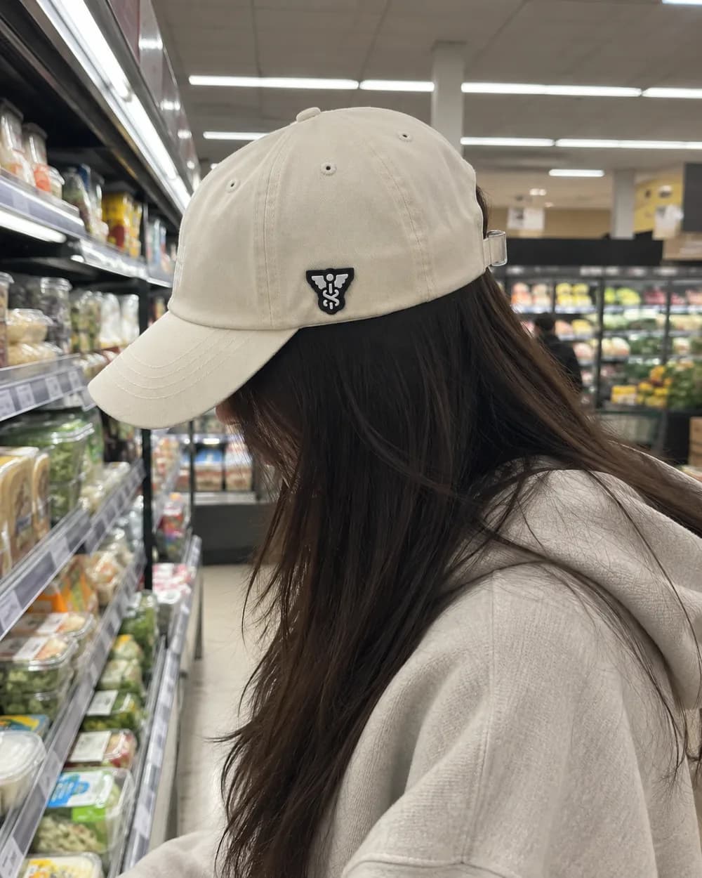 The Sallet worn in profile in a supermarket aisle, the symbol patch on its side. Face out of frame.
